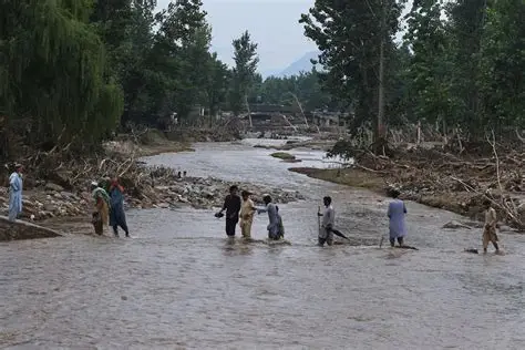 A flooded village in Pakistan showing damaged houses, collapsed roads, stranded families, and rescue workers helping victims during the 2025 monsoon floods.