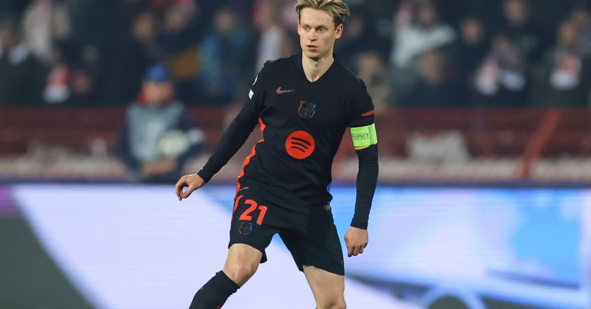 "Frenkie de Jong wearing Barcelona’s black away kit with red details and the captain’s armband, controlling the ball during a UEFA Champions League match. The stadium background is blurred with fans in the stands."